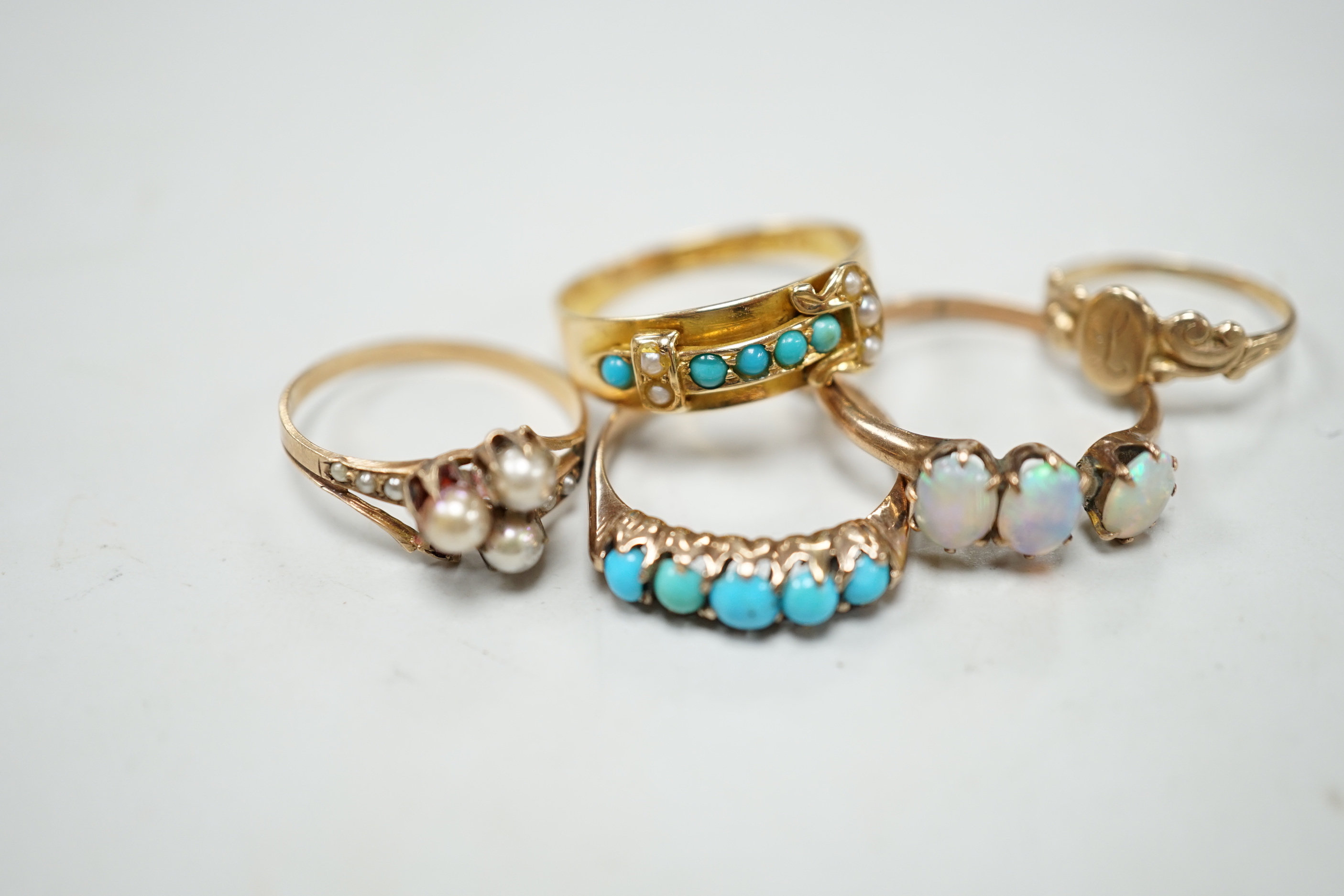 A late Victorian 18ct gold, turquoise and seed pearl set buckle ring, size P and four other yellow metal rings including gem set, gross weight 9 grams (a.f.).